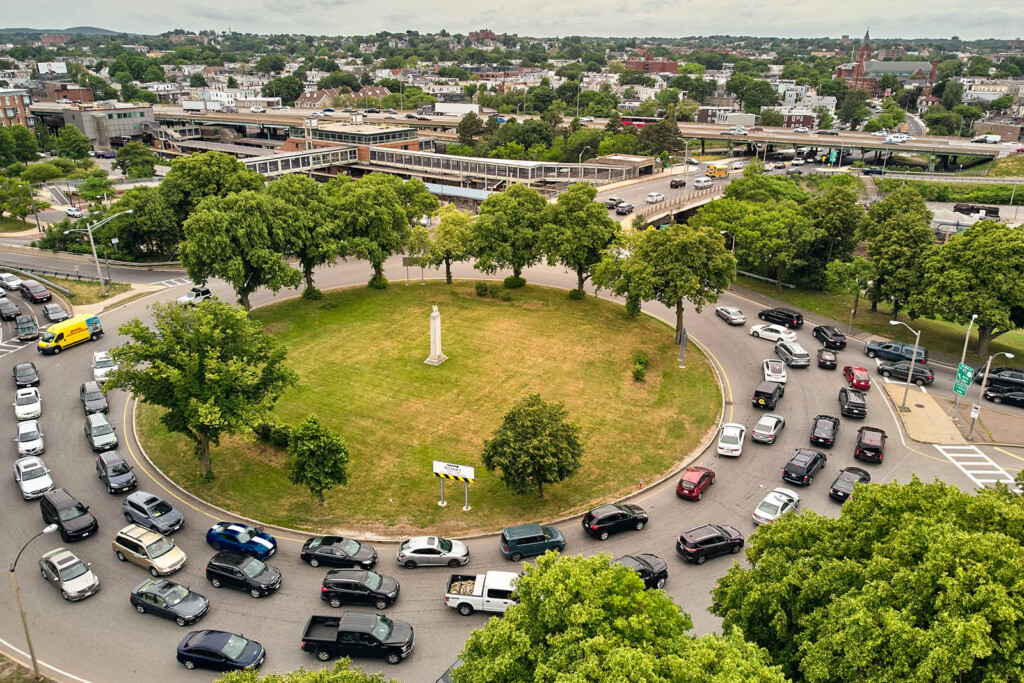 Busy rotary with lots of traffic with cars with a highway in a distance