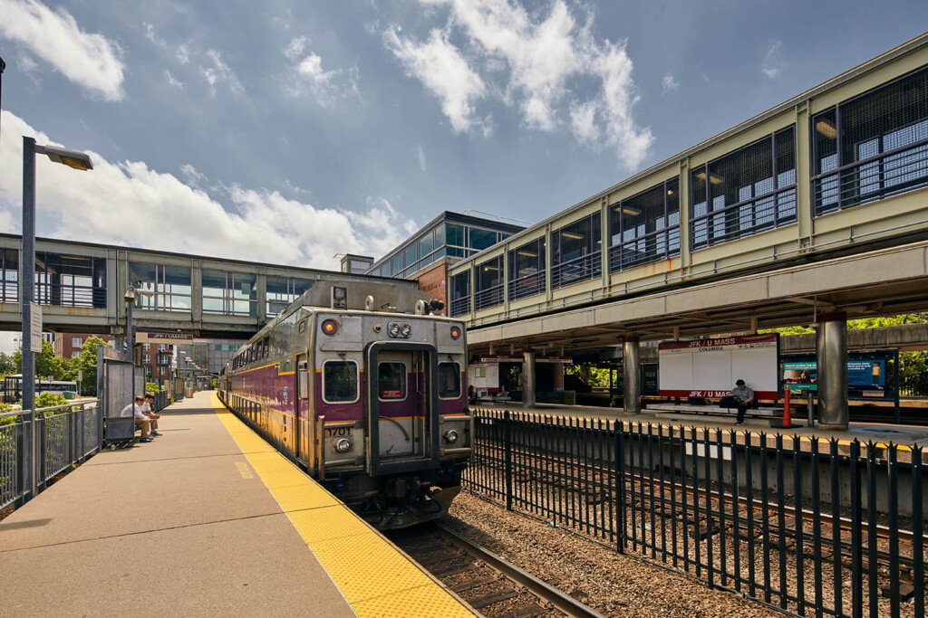 Photo of a train leaving a platform with two school age boys sitting on a bench