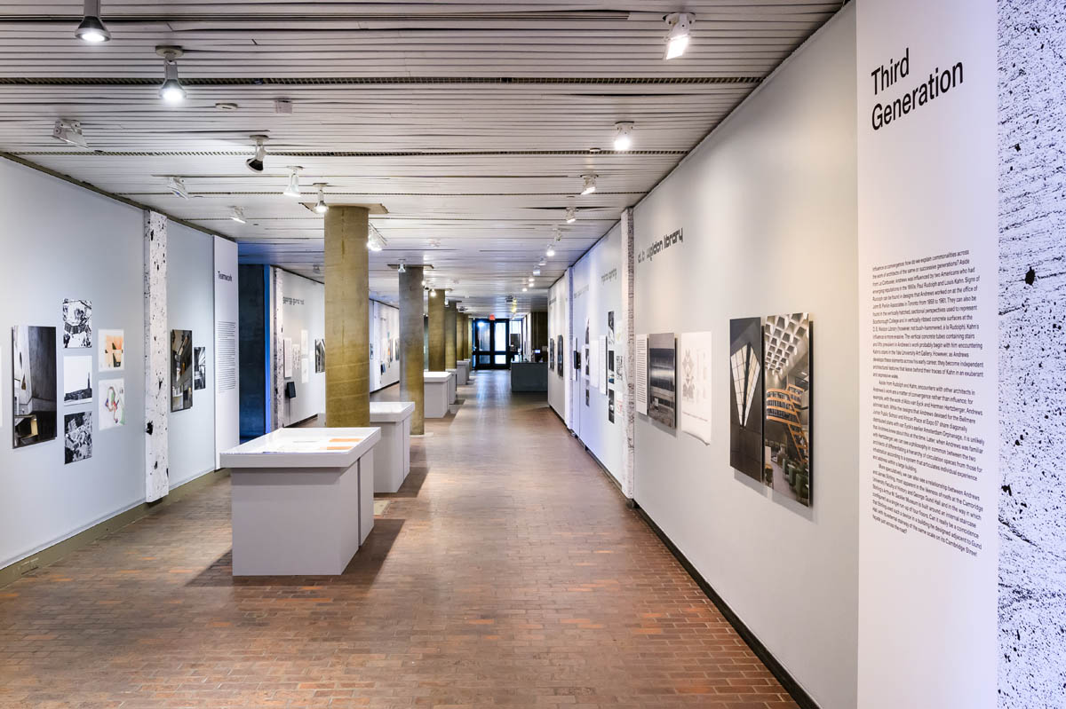 A long view down the exhiibiton corridor with diplay cases separated by and inline with cement columns.