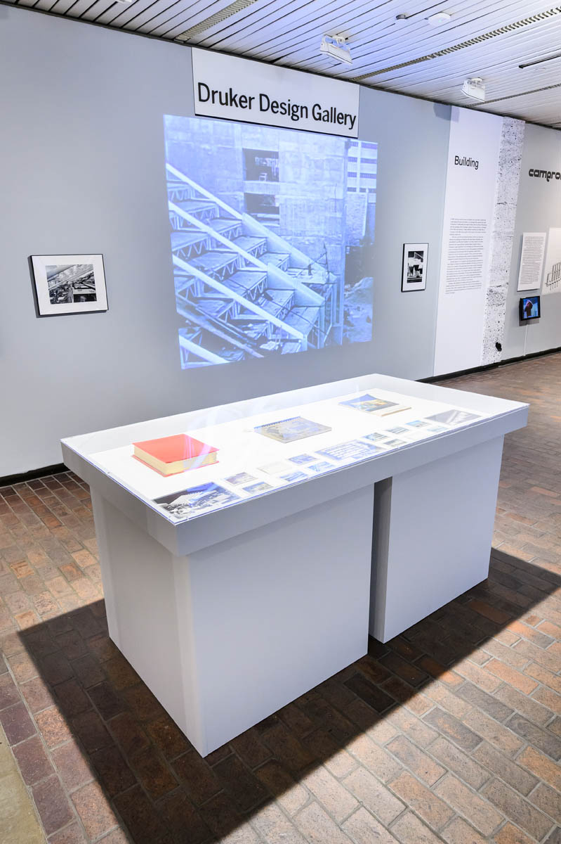 A display case, and an exhibition wall featuring a video projection.