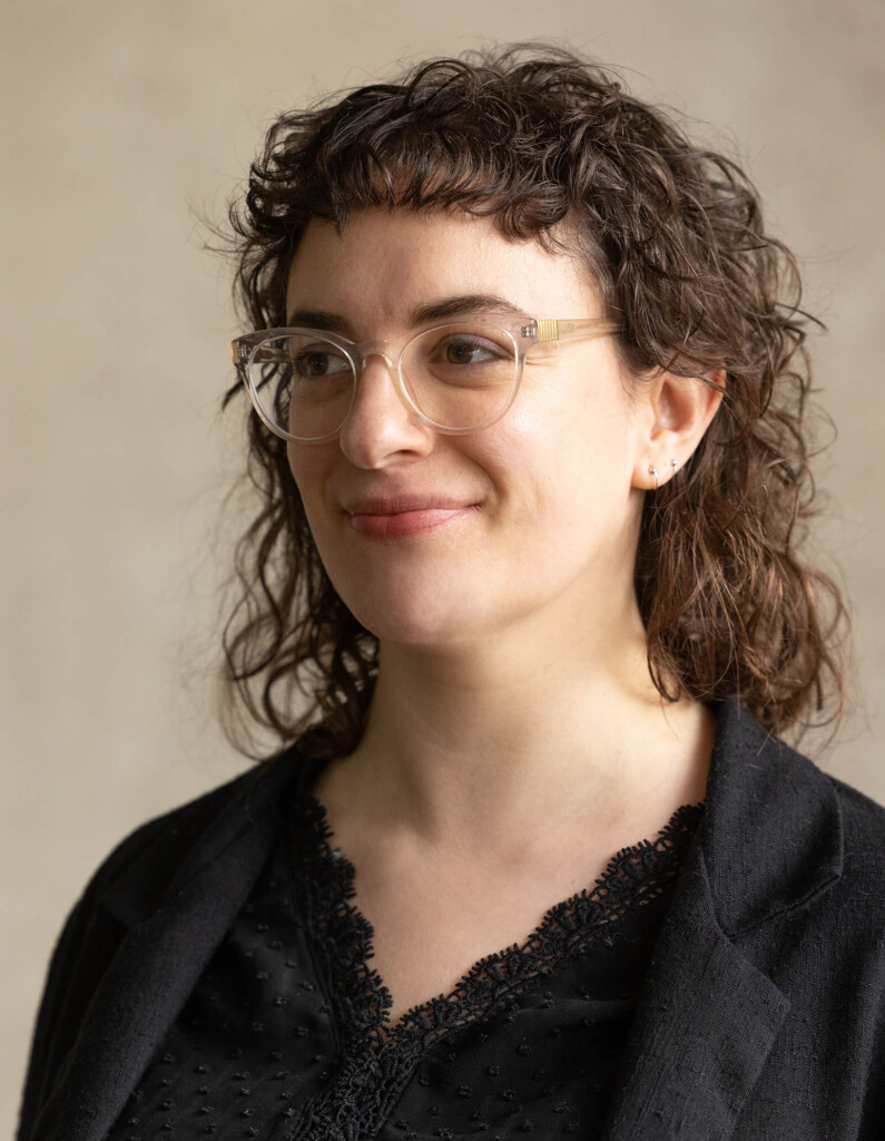 Headshot of a caucasian female, smiling and looking away from the camera into the distance