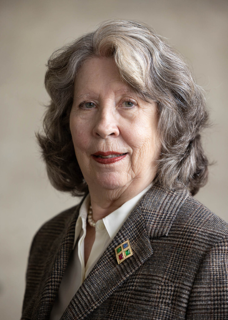 Headshot of caucasian female with gray hair, smiling at the camera