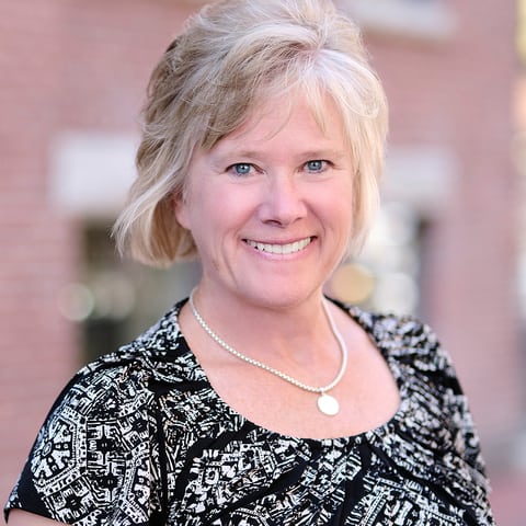 Headshot of Jean Barrett looking into the camera and smiling while earing a black and white top.