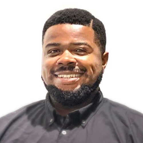 Laier-Rayshon is a Black man with dimples smiling at the camera. He has a full beard and parted hair.