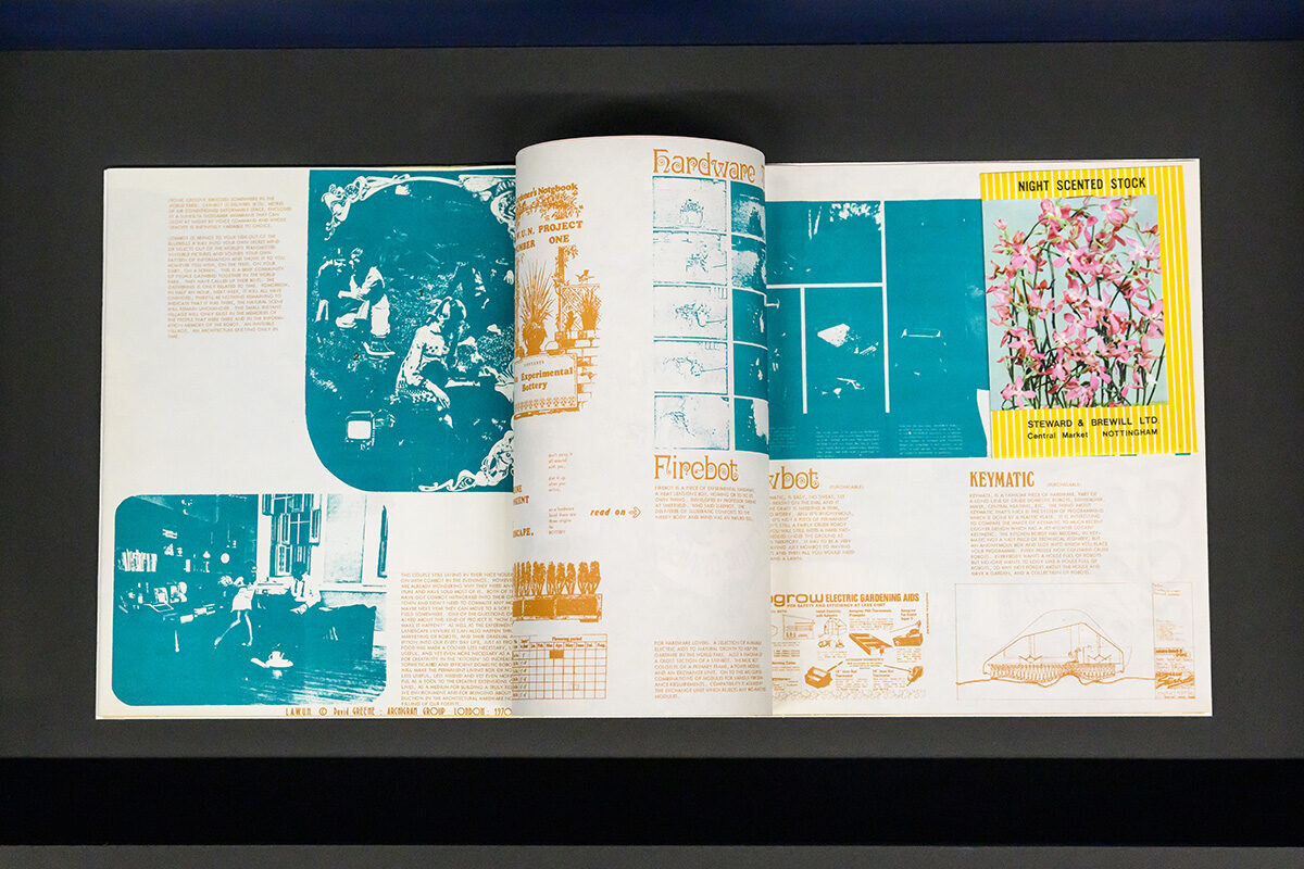 An open book with cyanotype images, orange stylized text, and an image of a seed packet of pink flowers.
