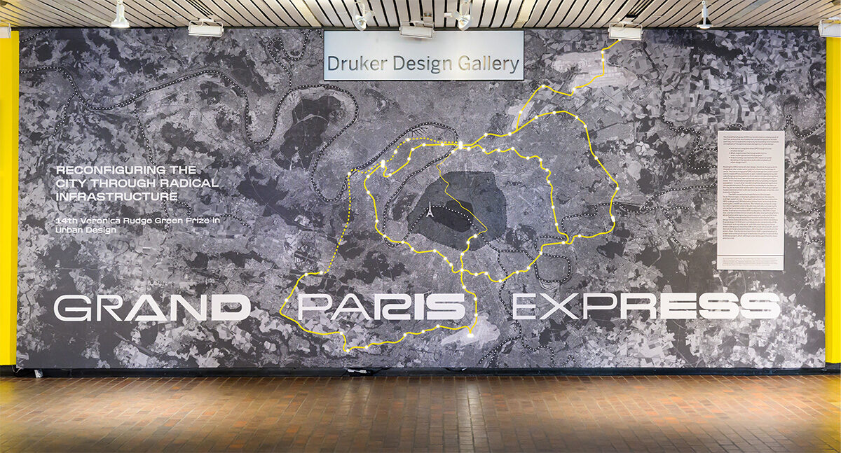 A view of the exhibit in Druker Design Gallery, showing a wall with a large aerial map of Paris and yellow lines delineating the area of the project.