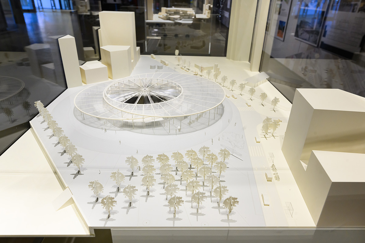 Architectural model of a train station exterior built of multiple round canopies, surrounded by trees and buildings.