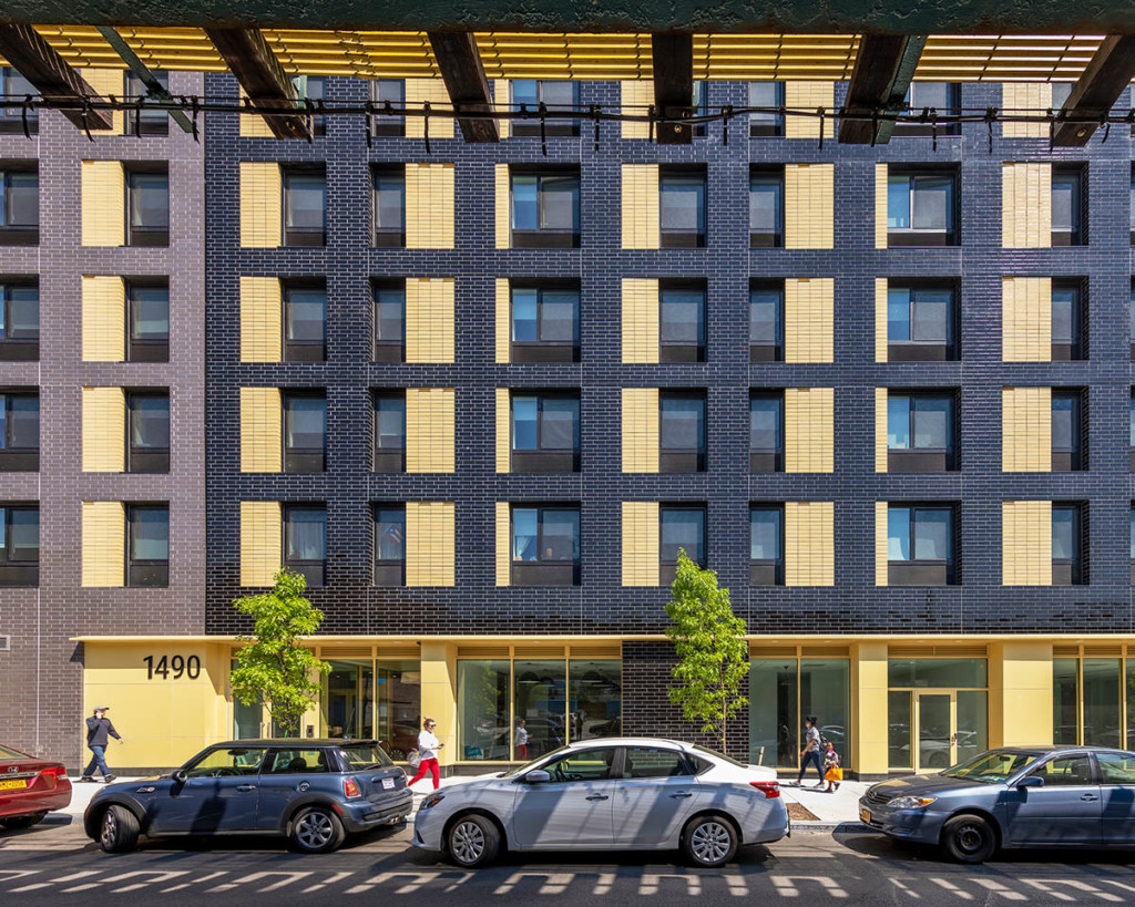 A view of the facade of a yellow and gray building, from the street.