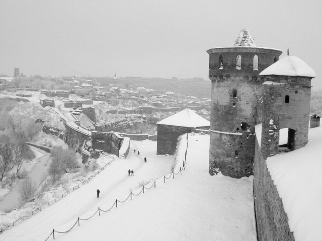 Aerial view of castle tower ad surrounding land; snow blankets the scene