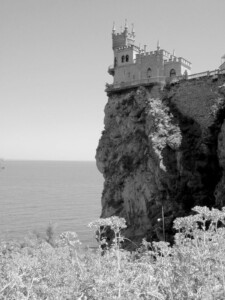 Photo of castle on the edge of a cliff bluff over ocean water.