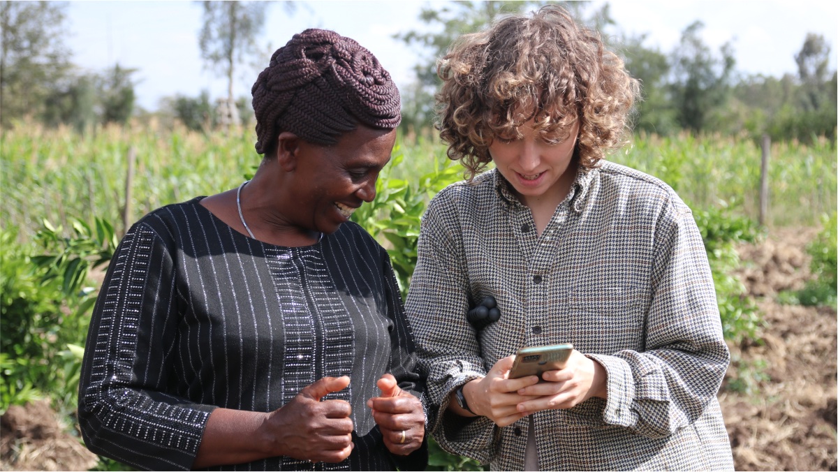 A photo of a Kenyan farmer with Rebecca, a GSD student, using a smartphone in a field.