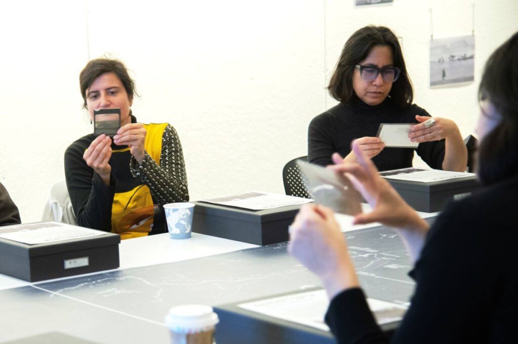 Several people look at photos around a table.