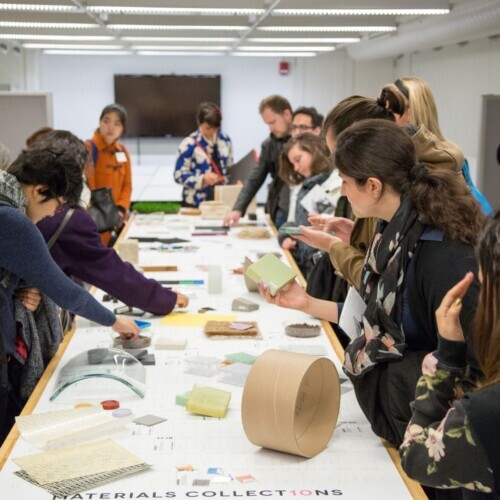 A group of students looks at physical objects on a table, which are part of the Materials Collections.