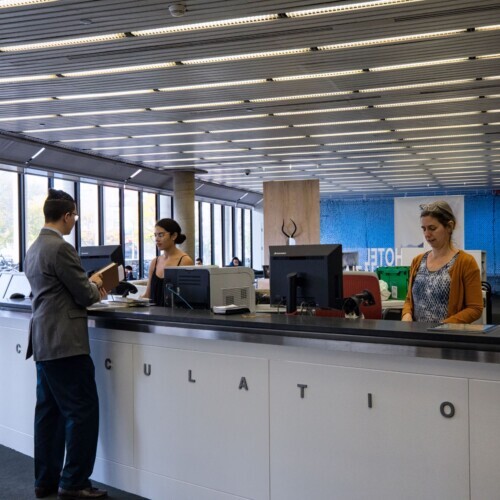 People standing at the circulation desk at Loeb Library.