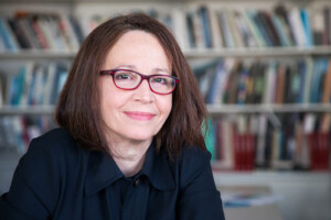 Portrait of Anita Berrizbeitia, who wears glasses and a black shirt.