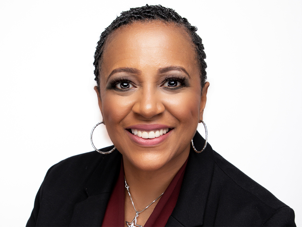 Headshot of Angela D. Brooks from the shoulders up wearing a black suit jacket, a maroon blouse, and silver jewelry.