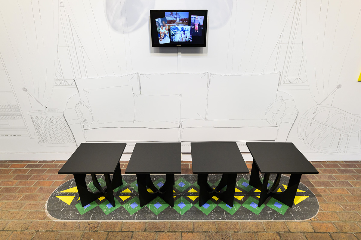 Four black stools in front of a line drawing of a couch and a video screen showing family photos.