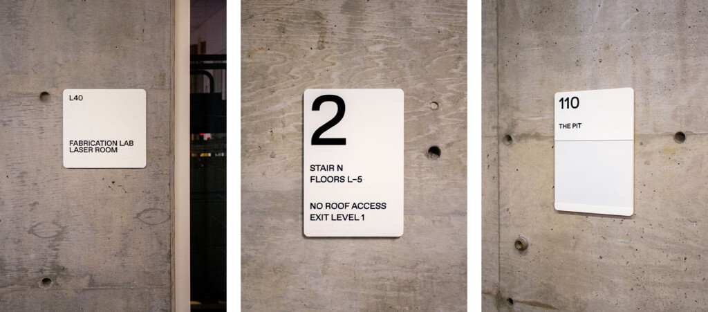 Wayfinding signs displayed on the concrete walls of Gund Hall.