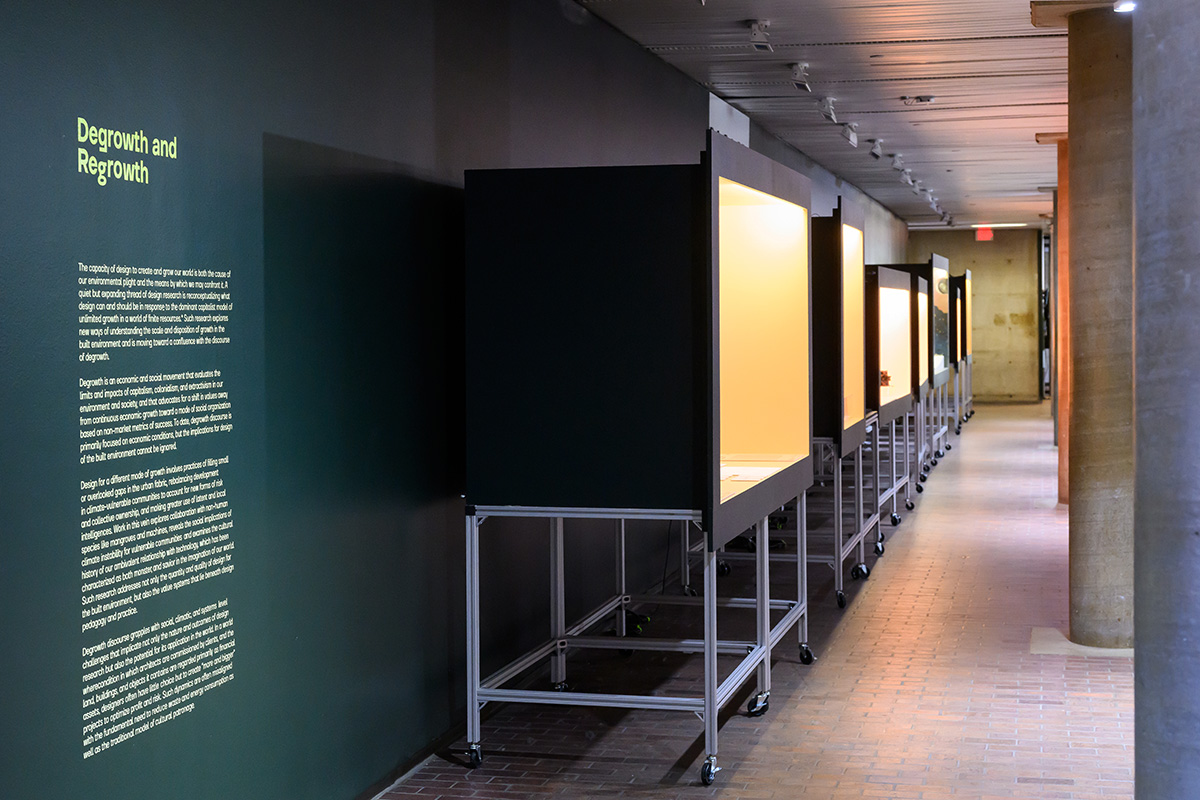 A view inside Druker Design Gallery, showing a line of lit display cases along a wall.