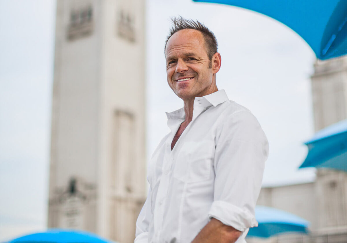 Picture of Claude Cormier MDes '94 in a white shirt outside with white and blue building background