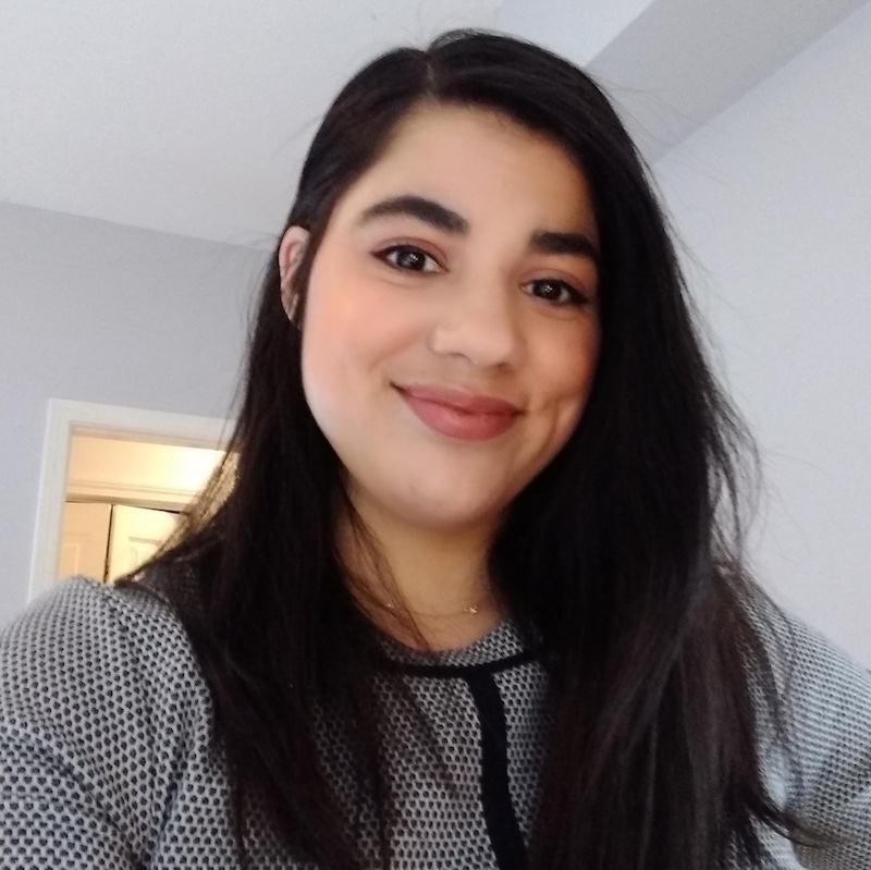 Headshot of Raquel Rivera looking at the camera and smiling while wearing a black and white top.