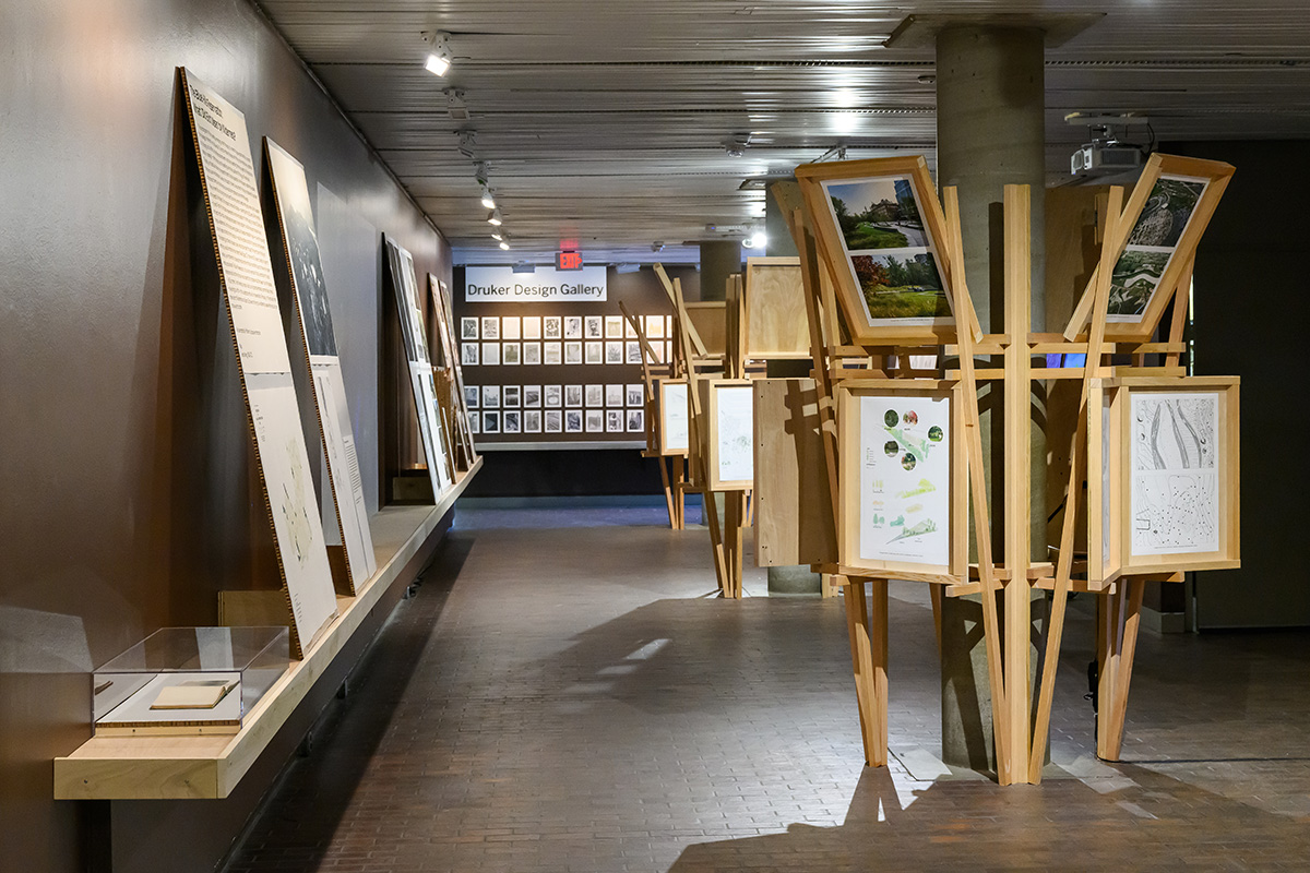 A view inside Druker Design Gallery showing wooden structures with display panels built around the columns and a shelf with display panels along the wall.