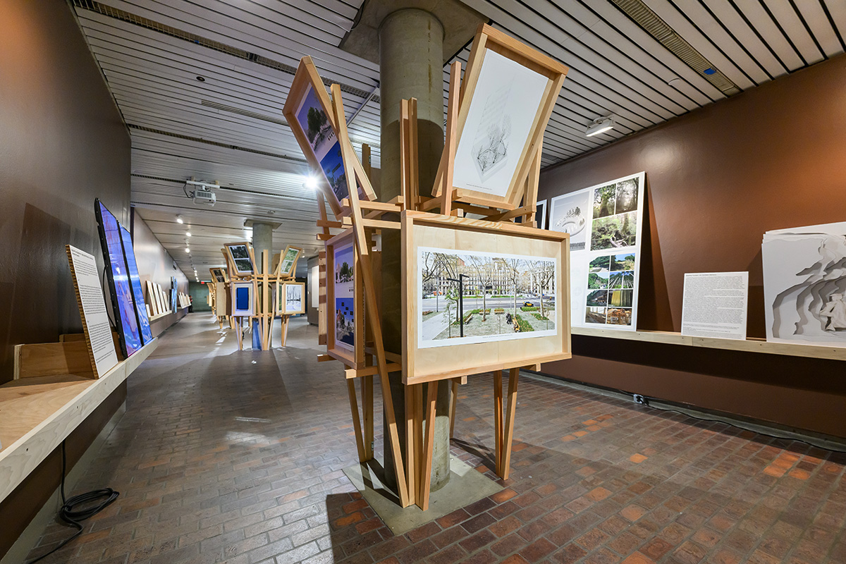 A view inside Druker Design Gallery showing wooden structures with display panels built around the columns and shelves with display panels along the walls.