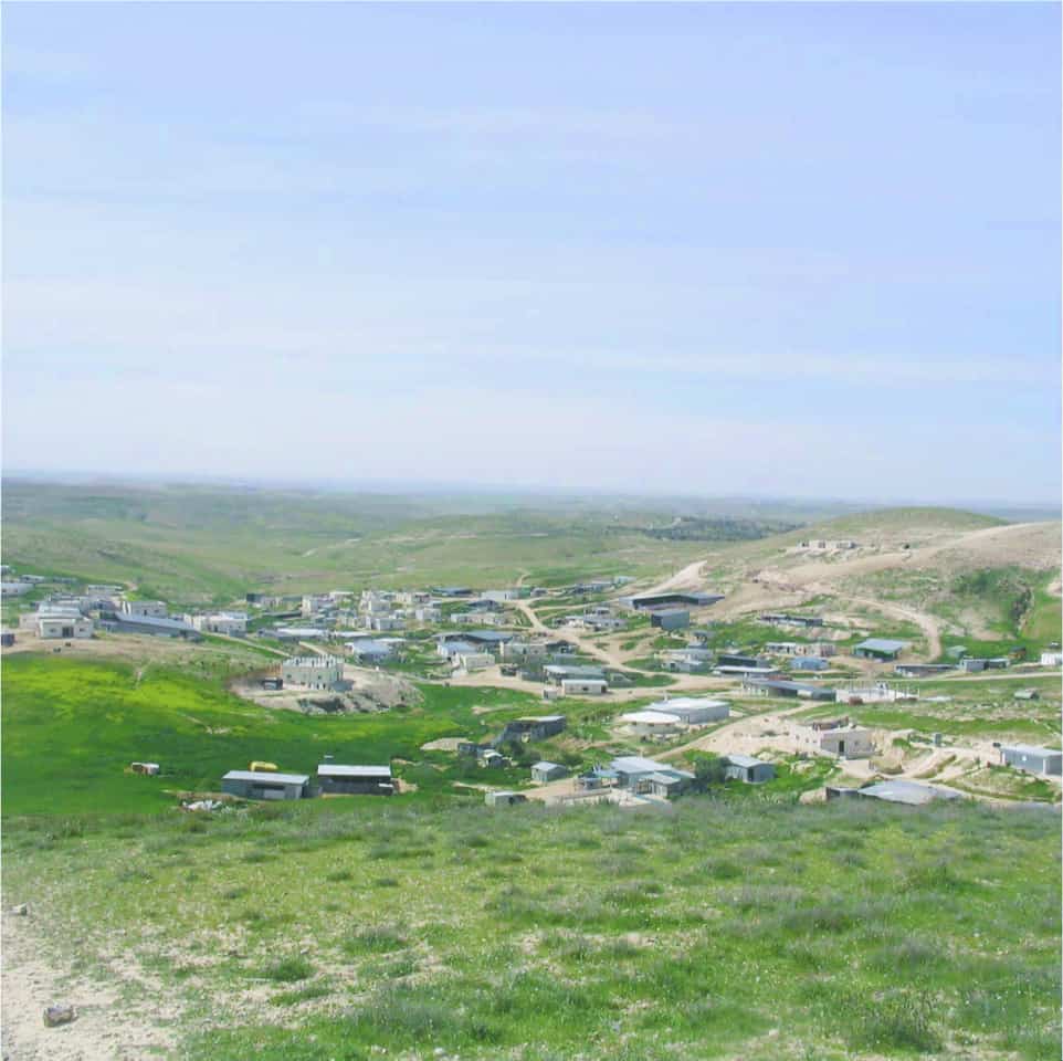 Photograph of a desert field with homes and small buildings scattered throughout.