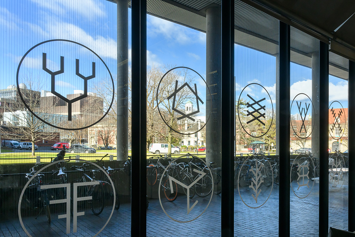 A view of the windows in Frances Loeb Library adorned with a variety of symbols.