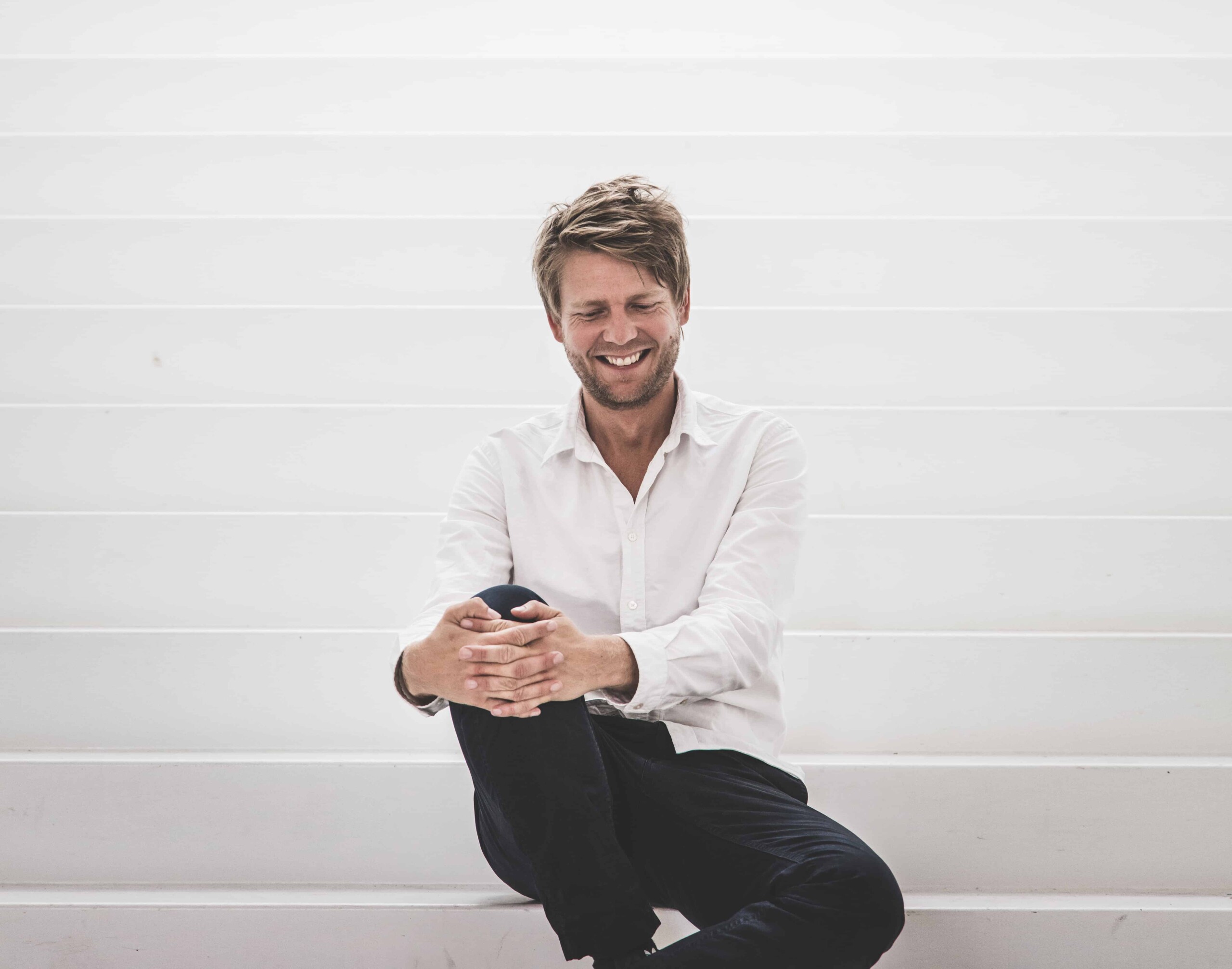 Photo of Dan Stubbergaard seated on gray to white gradient steps and smiling