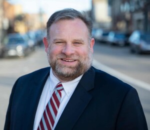 Outdoor Headshot of Mayor Cory Mason on a car-lined street.