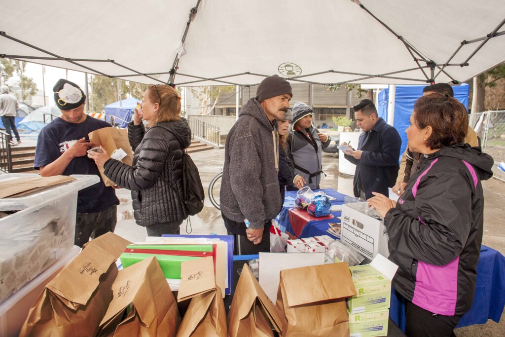 Photo of individuals gathered under a tent with tables.