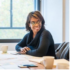 Photo of Toni Griffin seated at a table, smiling