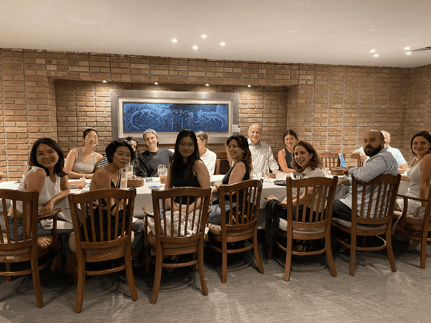 A group of people sit at a long table and smile for the camera.