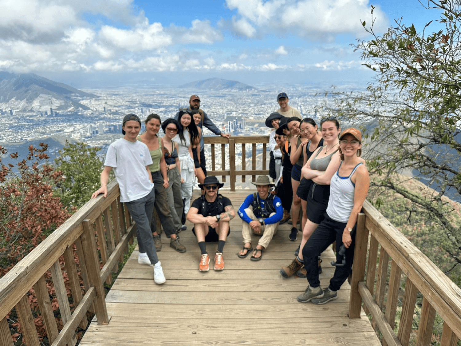 People standing on a platform at the top of a mountain. Below them is a view of a city below.