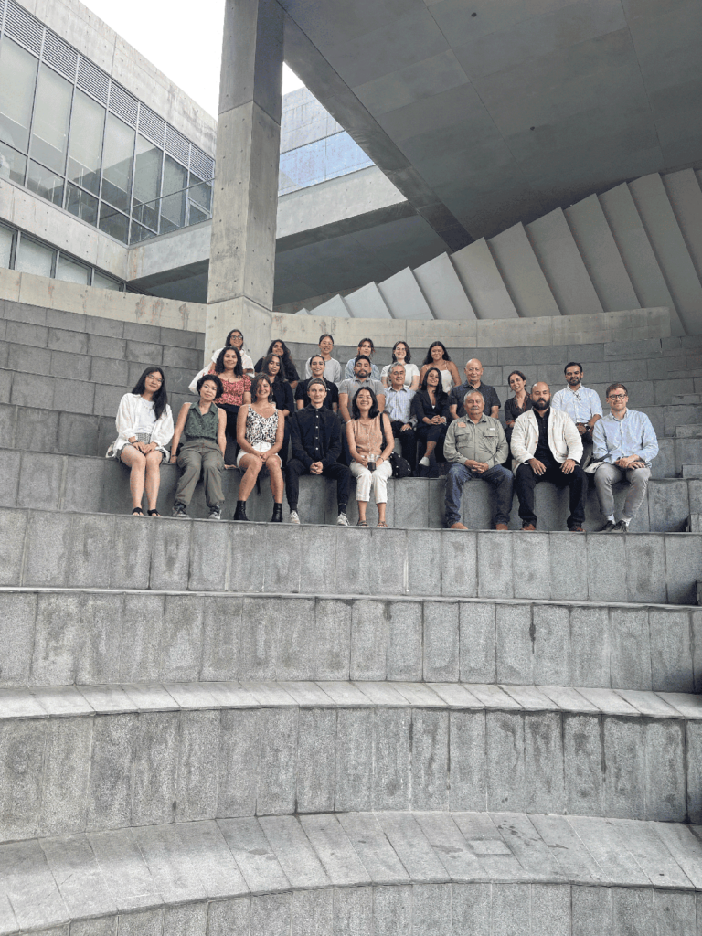 A group of people sit in a concrete outdoor amphitheater.