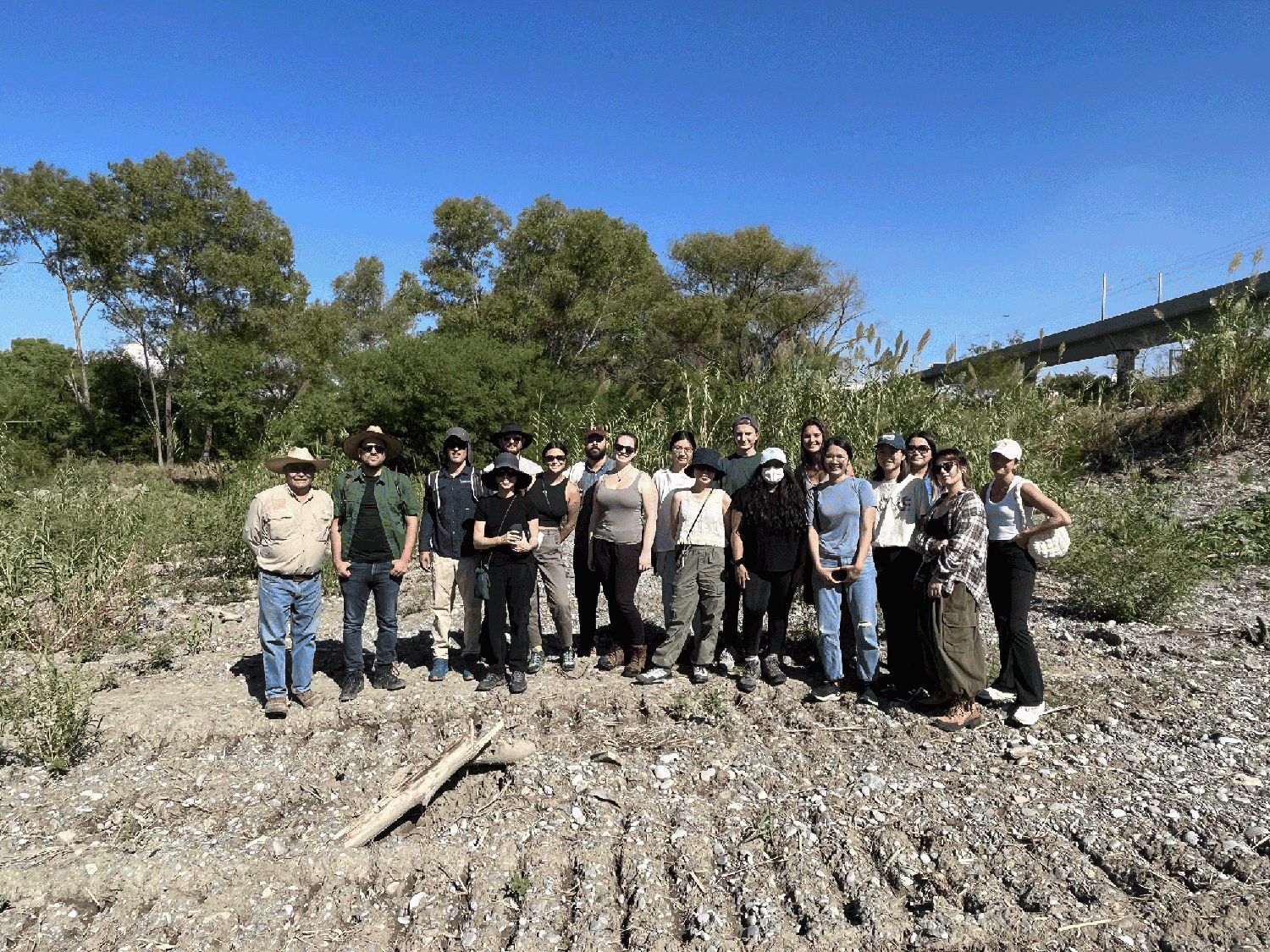 A group of people standing on a dry riverbed.