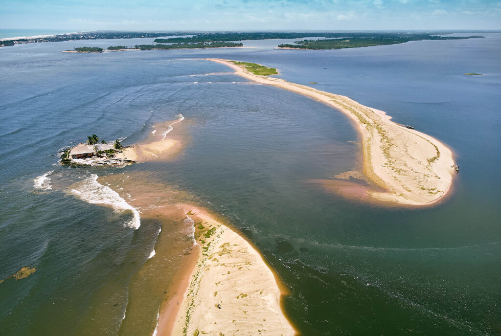 Aerial photo of a river with three sandy islands and land in the far distance