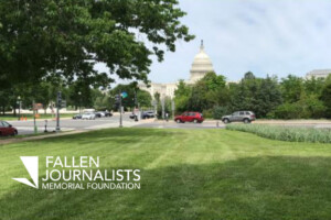 A view of the US Capitol building with a patch of green grass in the foreground. The image is watermarked with Fallen Journalists Memorial Foundation.