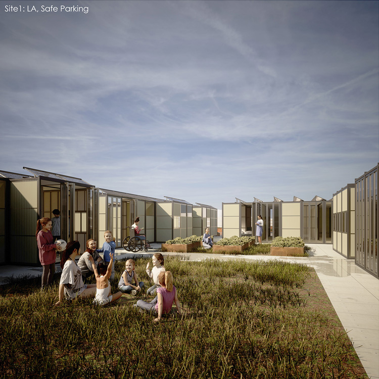 A group of children sit in a small grass open space. The area is surrounded by beige modular buildings.