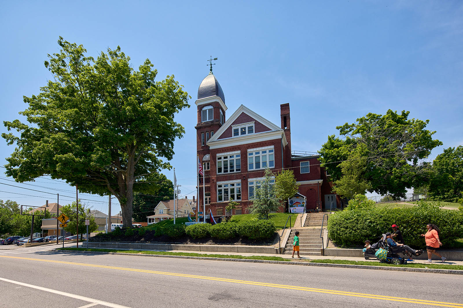 A photo of a City Hall in Central Falls, RI with a family walking in front of it.