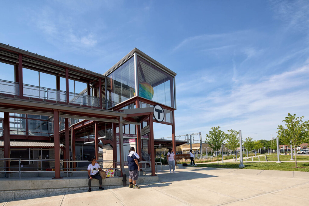 A photo of a train station with people in front of it.