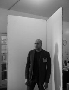 Black and white photo of David Hartt standing beside a folded canvas structure