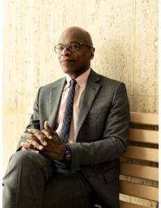 Portrait of Maurice Cox seated on a bench