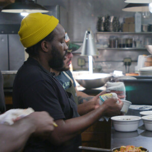 Image of Tunde Wey with others in kitchen