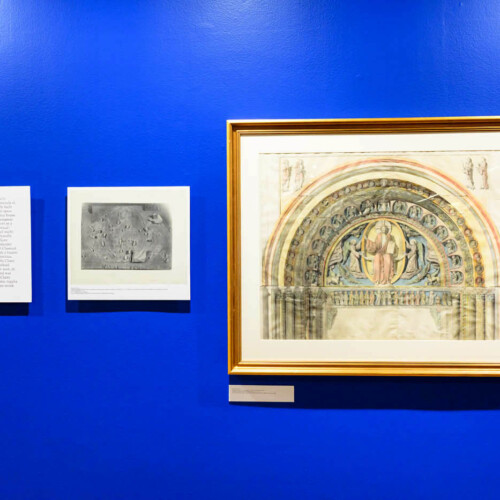 A wall with a framed painting, a refrence photo from which the painting was made, and text describing the process.