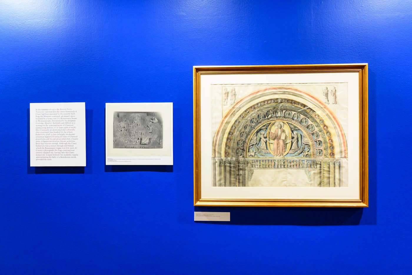 A wall with a framed painting, a refrence photo from which the painting was made, and text describing the process.