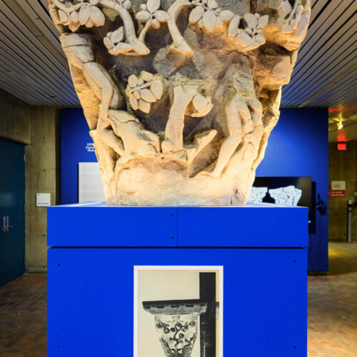 A replica of a column capital on a pedestal with a negative of an old photograph of the same capital.