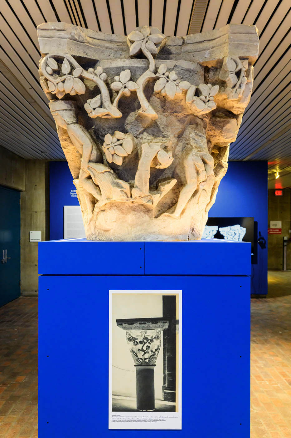 A replica of a column capital on a pedestal with a negative of an old photograph of the same capital.