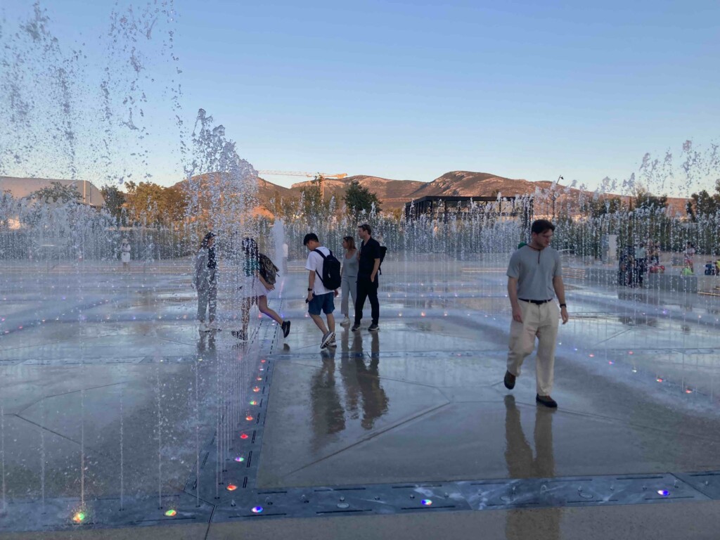 people walk around a fountain